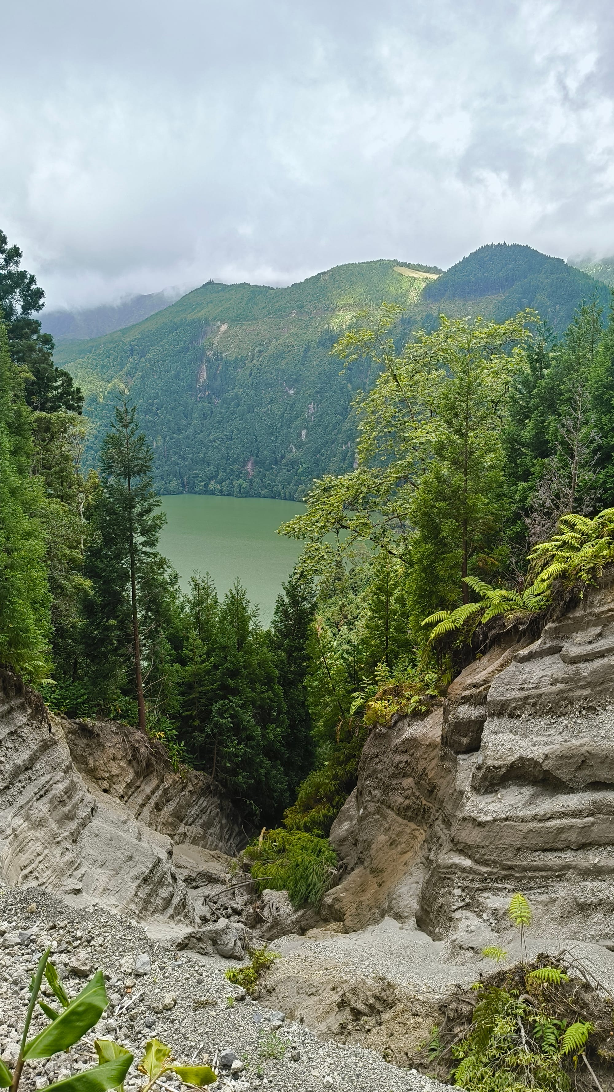 Shot from the cliff showing the hole that we could have fallen down with a lake and a mountain in the background