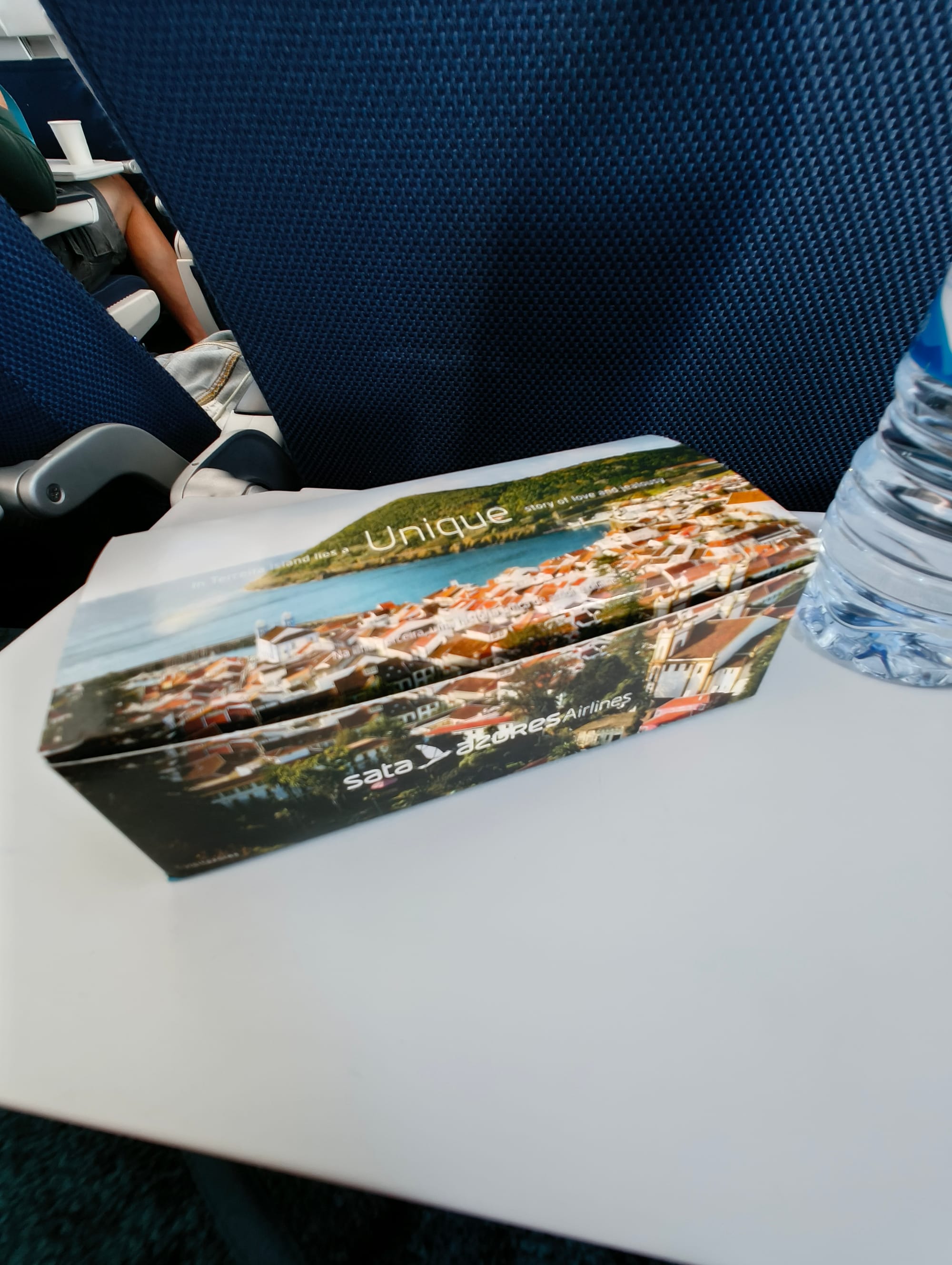 Box with food from Sata Azores airlines next to a water bottle. Both are placed on a plane stool.